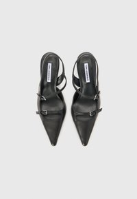 Mustan nahkaiset slingback-korkokengät terävillä kärjillä, joissa on kaksinkertaiset hihnat ja solkikoristelu. Sileä pinta ja tyylikäs muotoilu.
