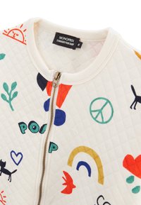 Veste blanche matelassée à zip, ornée de motifs abstraits colorés, y compris des animaux, un symbole de paix et des formes géométriques. Col côtelé.