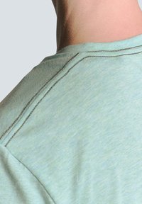 Lichtgroene crew neck t-shirt, met een zachte textuur en zichtbare stiksels langs de halslijn en schoudernaden.