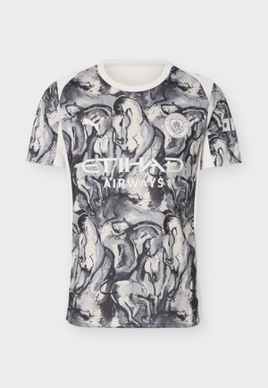 Ποδόσφαιρικη φανέλα της Μάντσεστερ Σίτι με ασπρόμαυρες εικονογραφήσεις αλόγων, το λογότυπο της Etihad Airways, το λογότυπο της Puma και το σήμα του συλλόγου στο εμπρός μέρος.