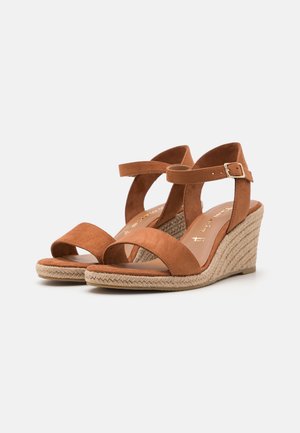 Brązowe zamszowe sandały na koturnie z obcasem owiniętym jutą, z paskiem na palce oraz regulowanym paskiem na kostkę z metalową klamrą.