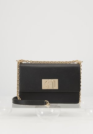Sac en cuir noir avec une finition texturée, une bandoulière en chaîne dorée et un ornement rectangular en métal doré sur le rabat avant.