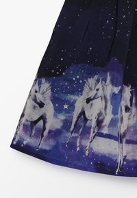 Tessuto blu scuro con unicorni bianchi su uno sfondo stellato notturno, con stelle argentate metalliche e una texture liscia. Design plissettato.