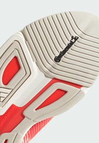Suela de zapato con una base de goma blanca texturizada que presenta surcos profundos. Detalles de diseño en rojo y el logo de "Continental".