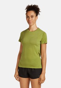 Zielona, krótkotalirowa koszulka sportowa z teksturowanej tkaniny, z okrągłym dekoltem. W połączeniu z czarnymi szortami, podkreślającymi sportowy styl.