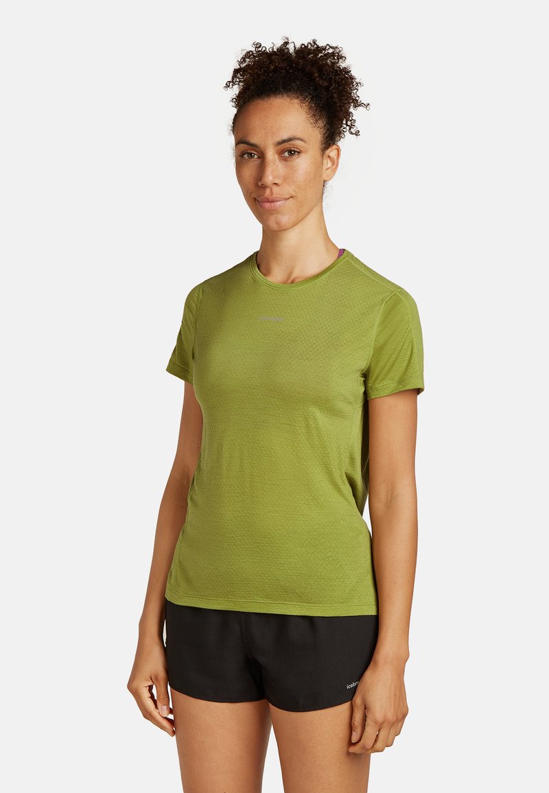 Zielona, krótkotalirowa koszulka sportowa z teksturowanej tkaniny, z okrągłym dekoltem. W połączeniu z czarnymi szortami, podkreślającymi sportowy styl.