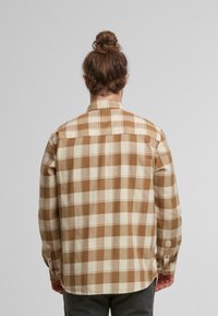 Kariertes Flanellhemd in Braun und Creme mit knöpfbaren Manschetten und geradem Schnitt. Es verfügt über einen klassischen Kragen und eine angenehme, weiche Textur.