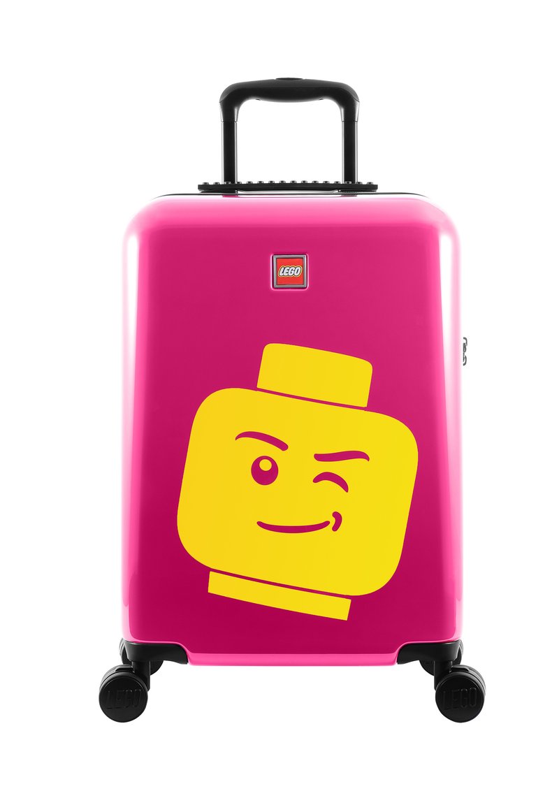 Hard-shell pink suitcase with black wheels. Features a large yellow LEGO head graphic and a small LEGO logo on the front.