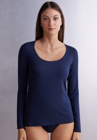 Långärmad topp i marinblått, tillverkad av smidig, stretchig tyg med rundad halsringning och enkel design, lämplig för lager-på-lager eller vardagsbruk.