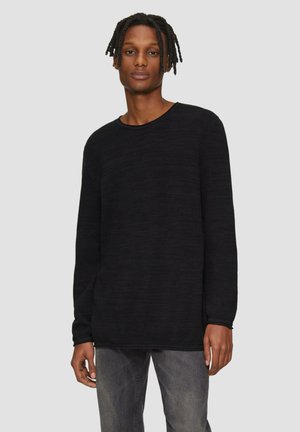 Zwarte lange mouwen crewneck trui van een textuurstof, met een ontspannen pasvorm en ribgebreide manchetten, gecombineerd met donkere jeans.