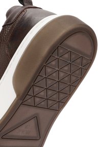 Suela de zapatilla de cuero marrón con media suela blanca. La suela de goma texturizada presenta un patrón triangular para agarre y tracción.