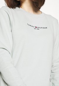 Jasno miętowa bluza z długim rękawem, okrągłym dekoltem i haftowanym logo "TOMMY HILFIGER EST. 1985" na przodzie. Miękka w dotyku.