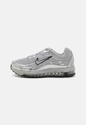 Srebrno-szary but do biegania z czarną podeszwą, widoczną poduszką powietrzną i czarnym logo Nike po boku, na białym tle.