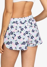 Shorts floraux avec un arrière-plan pastel présentant des fleurs roses et navy, taille élastique, coupe décontractée et ourlet arrondi.