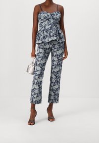Blommig peplumtopp i marinblått med ljusblå blommor, matchad med blommiga byxor. Har tunna axelband och en figurnära bodice.