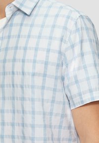 Kortekorte geruite blouse in lichtblauw en wit, met een geblokt patroon, knoopsluiting aan de kraag en een gestructureerde stof.