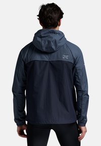 Marineblauwe lichtgewicht hoodie-jack met een contrasterend bovenpaneel. Beschikt over elastische manchetten en ademend materiaal voor buitenactiviteiten.