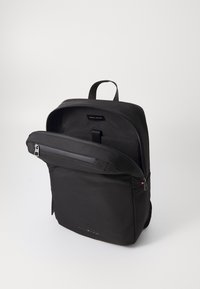 Zaino nero realizzato in tessuto liscio, dotato di una tasca frontale con zip, un scomparto principale con zip e una maniglia superiore per il trasporto.