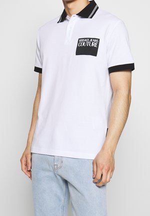 Weißes Poloshirt mit schwarzem Kragen und Akzenten an den Ärmeln. Verfügt über eine schwarze Tasche mit weißem "VERSACE JEANS COUTURE"-Text. Lockere Passform.
