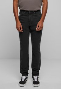 Juodos džinsinės keln�ės su tiesiomis kojomis, pasižyminčios klasikinio penkių kišenių dizainu ir mažu logotipo etikete ant priekinės kišenės.