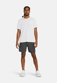 Camiseta blanca de manga corta, pantalones cortos deportivos grises con logo y zapatillas blancas. Diseño simple y tejido ligero adecuado para el deporte.