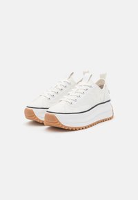 Sneakers bianchi in tela con una spessa suola bianca e suola in gomma. Presentano chiusure con lacci e un'apposita linguetta sul tallone. Linea di accentuazione nera sulla suola.