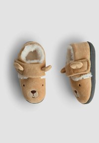 Bruna fluffiga tofflor med björnfacedesign, vit fake pälsfoder, små öron på sidorna och svarta gummisålar. Stängningsrem ovanför ankeln.