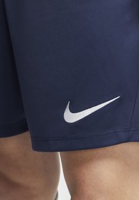 Pantalones cortos atléticos en color azul marino, confeccionados en una tela suave y ligera, con un logo de Nike en blanco en la parte inferior izquierda, que presenta detalles de costura limpios.