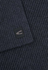 Marineblauwe geribbelde gebreide trui met een gestructureerd oppervlak; beschikt over een klein zwart label met een grijs logo aan de onderrand.