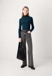Teal stripete genser med rullekrage, kombinert med høygravid svarte jeans og en svart plisserte totebag, iført med svarte sko.