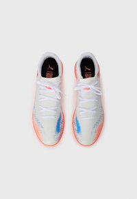 Une paire de chaussures de sport blanches avec des accents bleu et orange, des lacets blancs et des semelles intérieures noires arborant un logo Puma orange et un code QR.