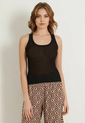 Black ribbed tank top with wide straps and textured hem, paired with patterned pants featuring geometric designs in pink, brown, and cream.