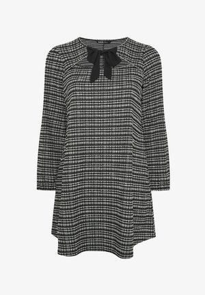 Tunic a scacchi bianco e nero con scollatura rotonda, caratterizzata da un accento di fiocco nero sul davanti e maniche a tre quarti. Tessuto morbido.