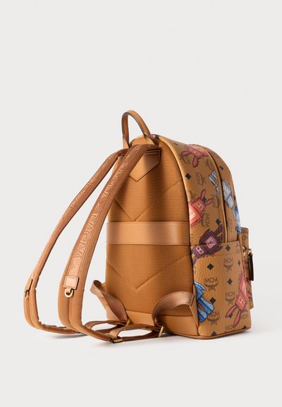 Καφέ σακίδιο πλάτης από συνθετικό δέρμα με πολύχρωμα λογότυπα, καπιτονέ υφή στην πλάτη, ρυθμιζόμενους ιμάντες και κλείσιμο με φερμουάρ. Διακριτικά μεταλλικά στοιχεία σε χρυσό χρώμα.