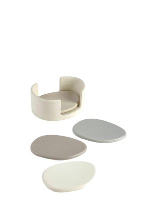 Rund beige sæbeskål med forhøjede kanter og tre ovale sæbebarer i nuancer af hvid, grå og lysebrun på hvid baggrund.