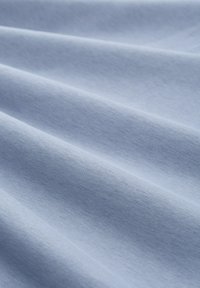 Țesătură de bumbac de culoare bleu deschis, cu o textură subtilă, având pliuri netede și fluente și un aspect uniform în întreaga sa extensie.