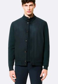 Giacca nera in maglia con colletto rialzato, chiusura frontale a sei bottoni, polsini e orlo a coste, caratterizzata da una texture liscia e un design casual.