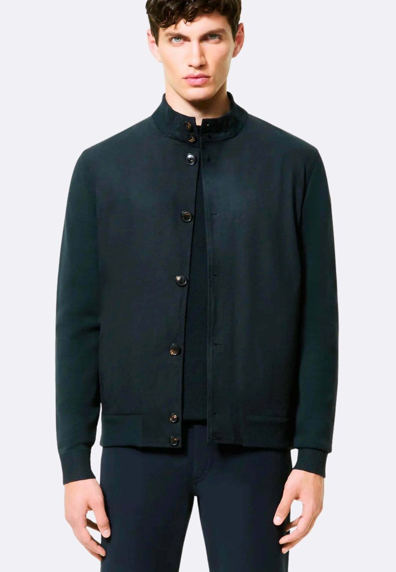 Giacca nera in maglia con colletto rialzato, chiusura frontale a sei bottoni, polsini e orlo a coste, caratterizzata da una texture liscia e un design casual.