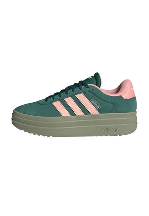 Baskets Adidas en daim vert avec des bandes roses, semelle épaisse beige et doublure intérieure rose. Chaussure décontractée d'extérieur avec lacets visibles.