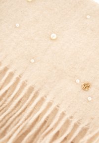 Écharpe beige en matière douce, ornée de perles éparpillées et d'une touche dorée. Les bords frangés ajoutent de la texture au design.