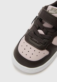 Baskets en cuir marron avec des accents rose clair, une boîte à orteils texturée, des détails perforés et des lacets noirs. Semelle en caoutchouc blanc avec des coutures.