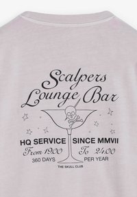 Camiseta de color rosa claro con texto gráfico negro e ilustración de una copa de cóctel con una calavera y huesos cruzados.