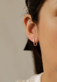 Srebrna kolczyk w kształcie obręczy o eleganckim, minimalistycznym designie. Gładkie, wypolerowane wykończenie odbija światło, podkreślając zaokrąglony kształt.