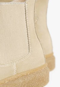 Stivali alla caviglia beige realizzati in suede e tessuto canvas, con cuciture a vista, una superficie texture e suola in gomma.
