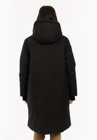 Abrigo largo negro con capucha acolchada, puños acanalados y un exterior suave. La parte trasera presenta un corte recto y un dobladillo ligeramente curvado.