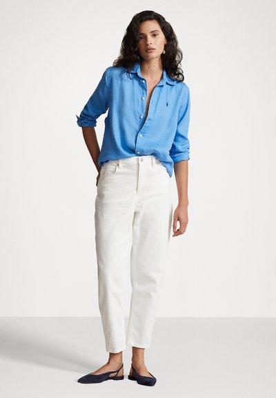 Light blue button-up shirt, white high-waisted pants, and navy flats. Smooth fabric, relaxed fit, and rolled sleeves.
