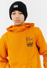 Oranžová fleecová mikina s čiernou grafikou horskej postavy a nápisom "PROTEST". Má klokanie vrecko a vysoký golier s kapucňou.