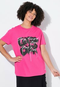 Fuchsia short-sleeve T-shirt made of cotton featuring a black graphic print with white text, placed against a plain background.