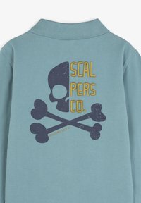 Camicia a maniche lunghe azzurro chiaro con una grafica di teschio e ossa incrociate in blu scuro, con la scritta "SCAL PERS CO." in giallo e un effetto invecchiato.