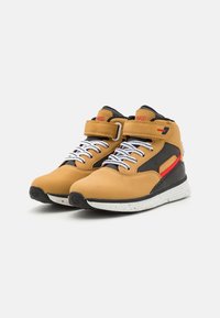 Sneaker sintetiche marroni a mezza altezza con accenti neri e rossi, dotate di lacci bianchi e una suola testurizzata per la trazione. Inclusa una fascia in velcro.